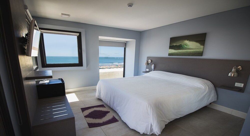 Dormitorio con cama grande, escritorio y ventana hacia la playa