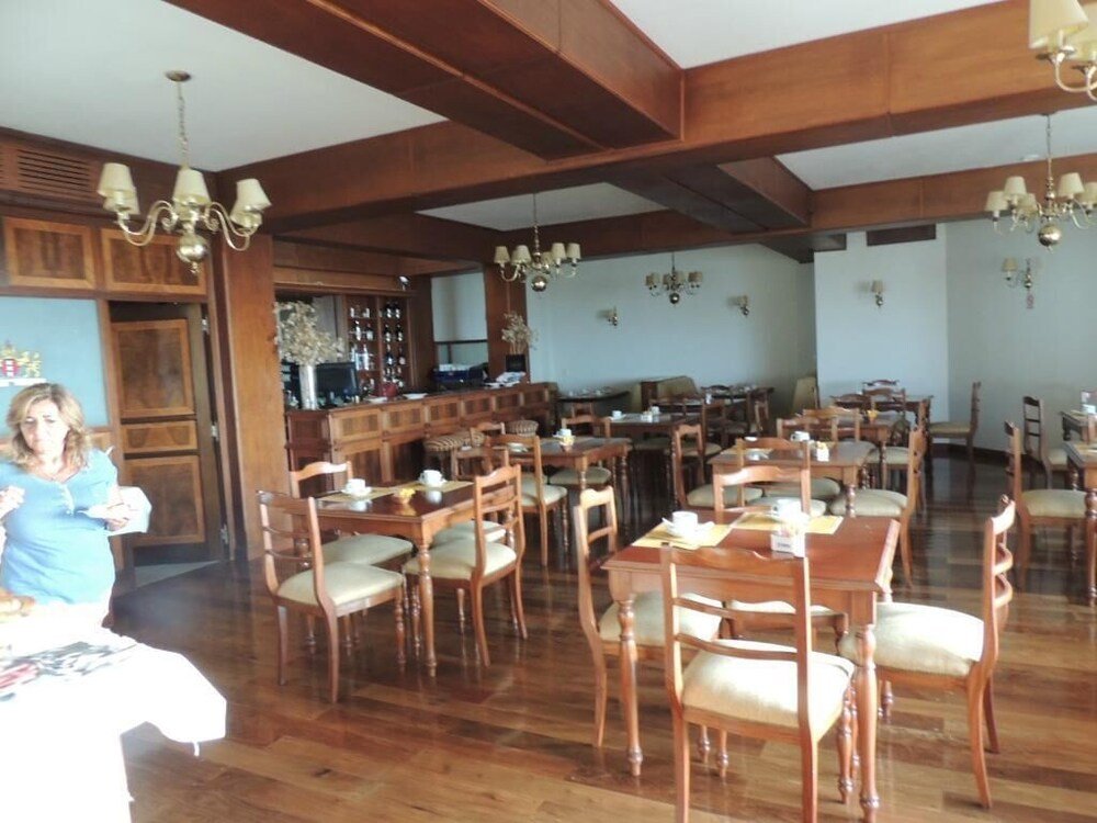 Comedor con mesas de madera, barra y lámpara de araña