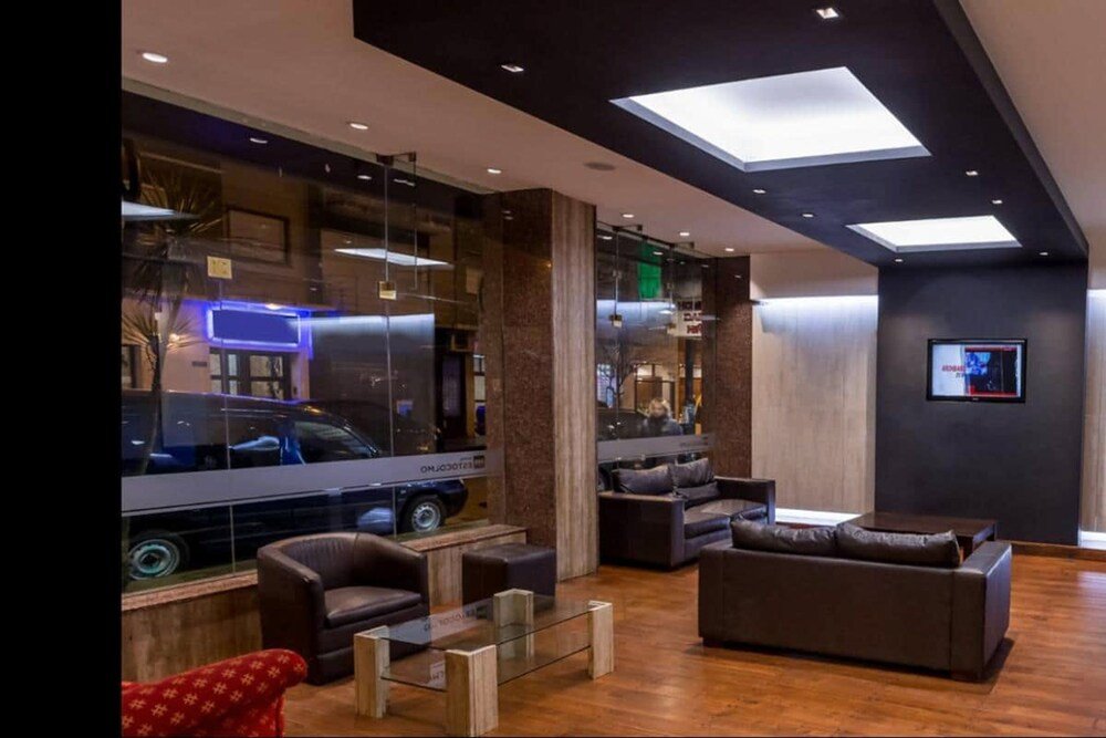 Hall moderno con pared de vidrio, sillones y televisor