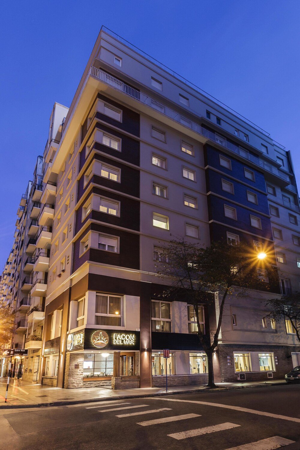 Fachada del hotel de varios pisos con balcones y local a la calle