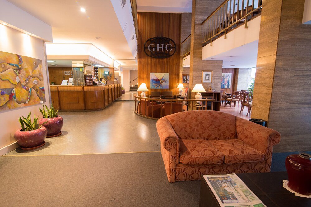 Hall con mostrador de recepción, sofá, plantas y escalera