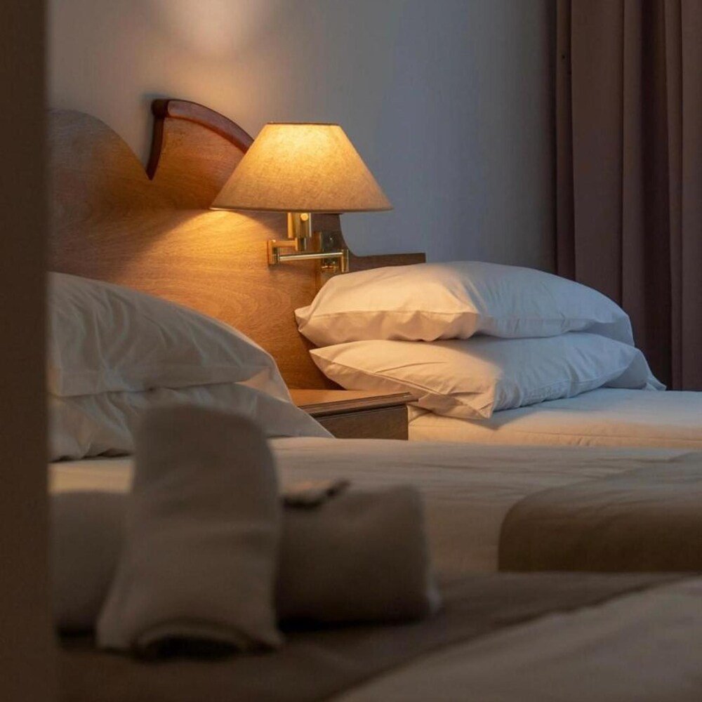 Cama bien tendida con ropa blanca y almohadones