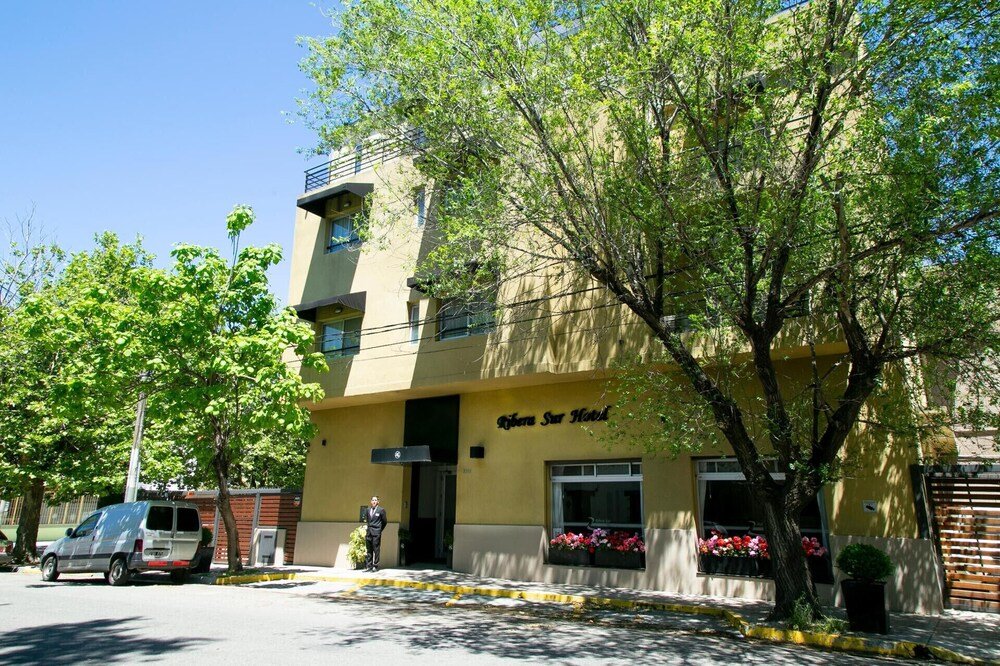 Edificio de frente amarillo con balcón y jardineras en las ventanas