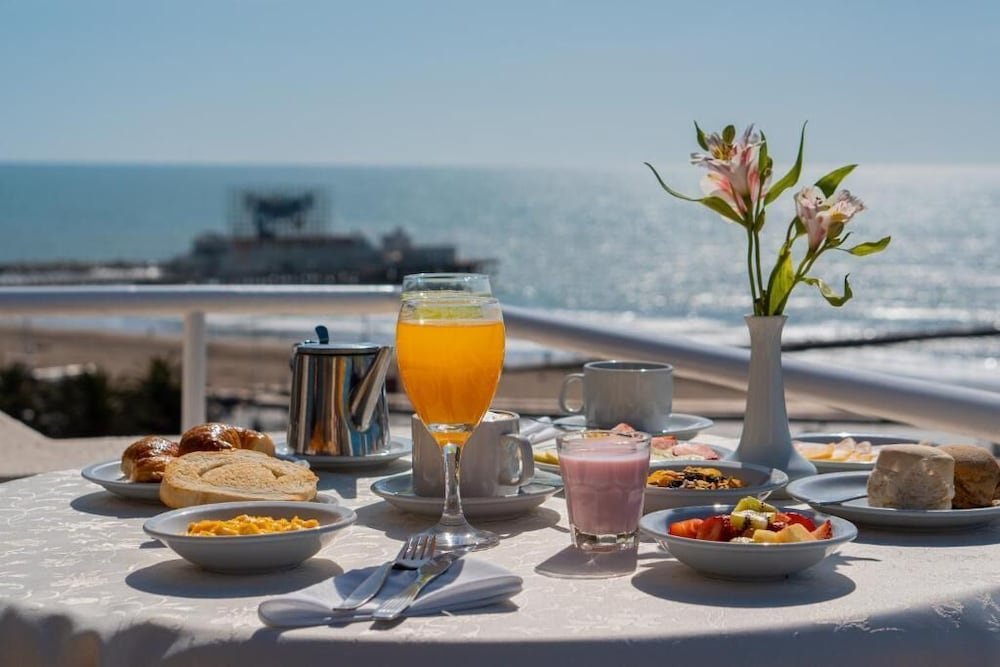 Mesa de desayuno con platos y bebidas frente al mar