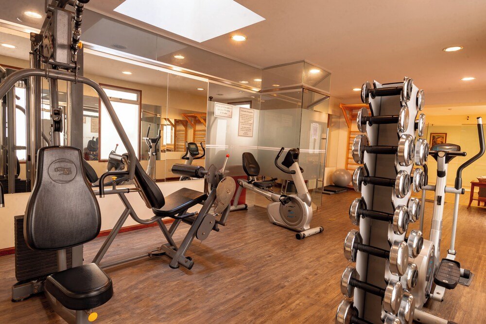 Gimnasio con equipos, espejo y piso de madera