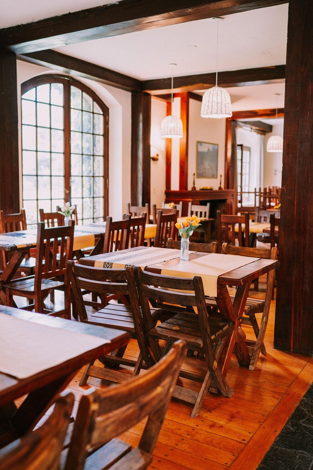Restaurante con mesas y sillas de madera, ventanales y lámparas colgantes